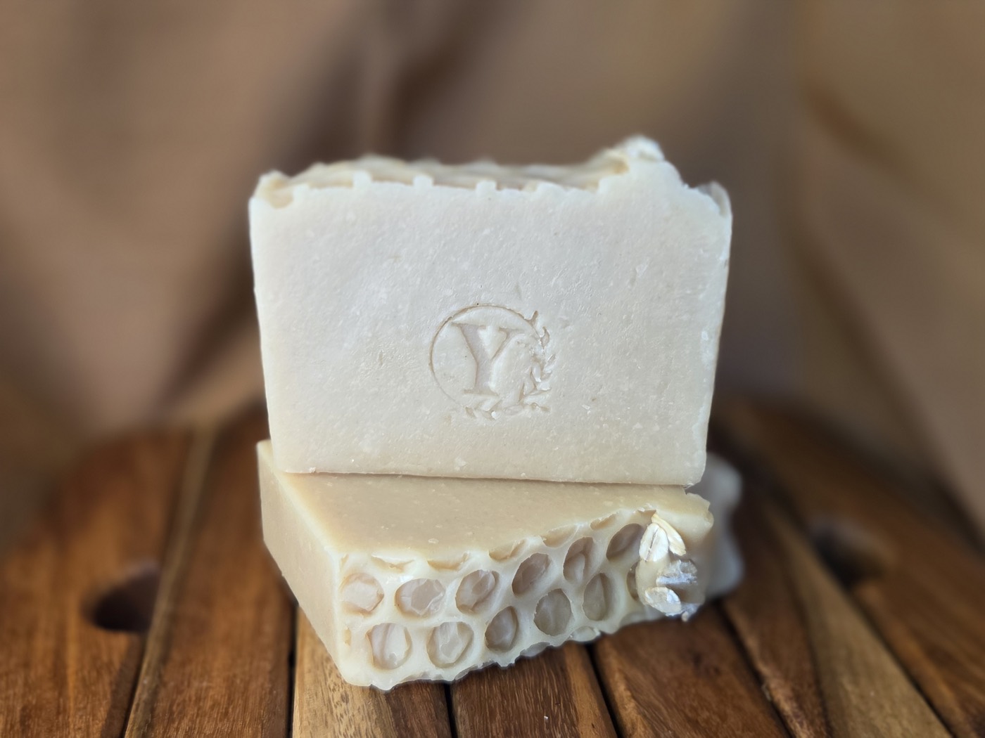 Cream-colored soap bar stamped with a Y, stacked on a honeycomb-textured bar