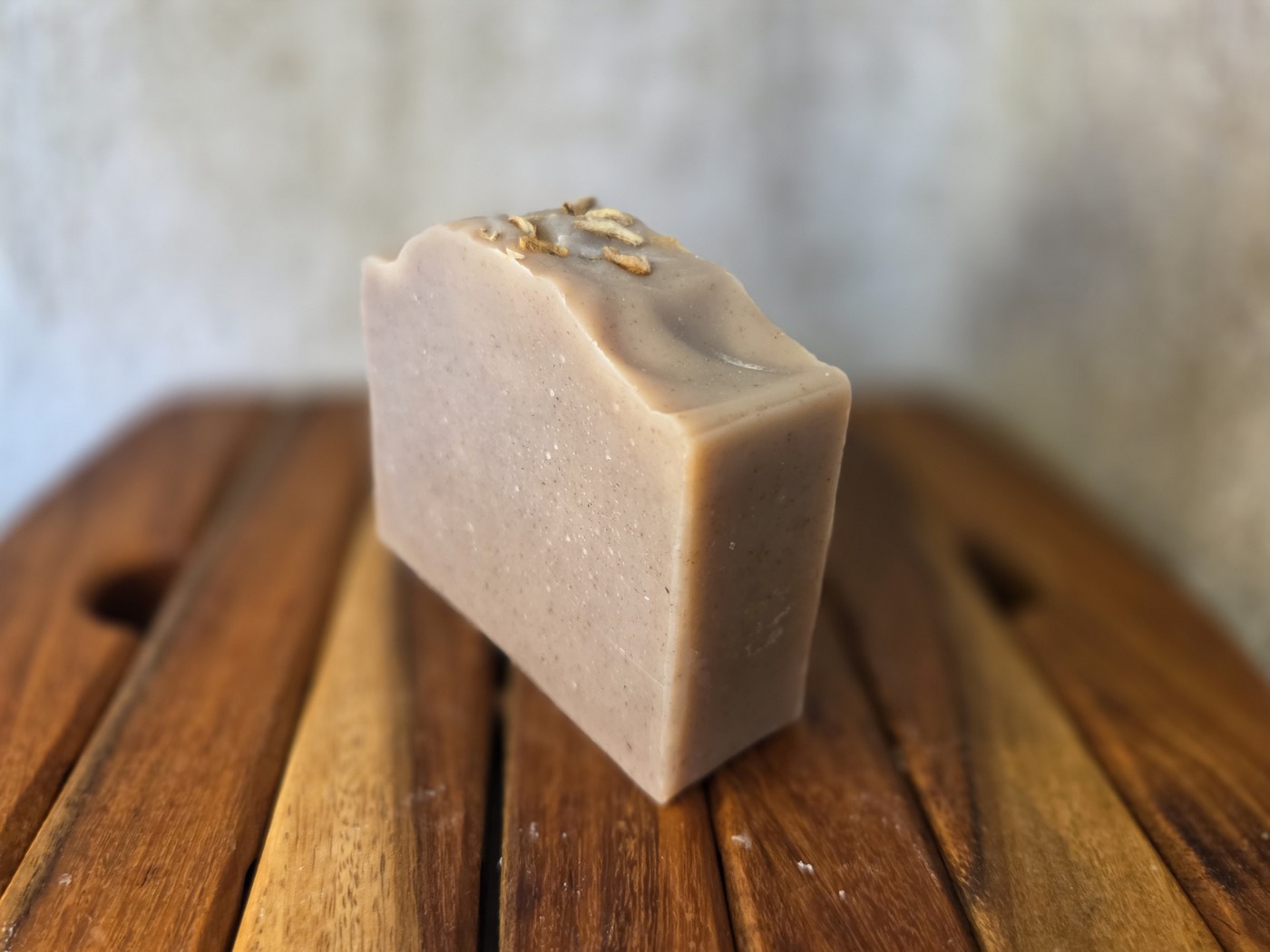 Blush-tan soap bar with oat flakes on a wavy top