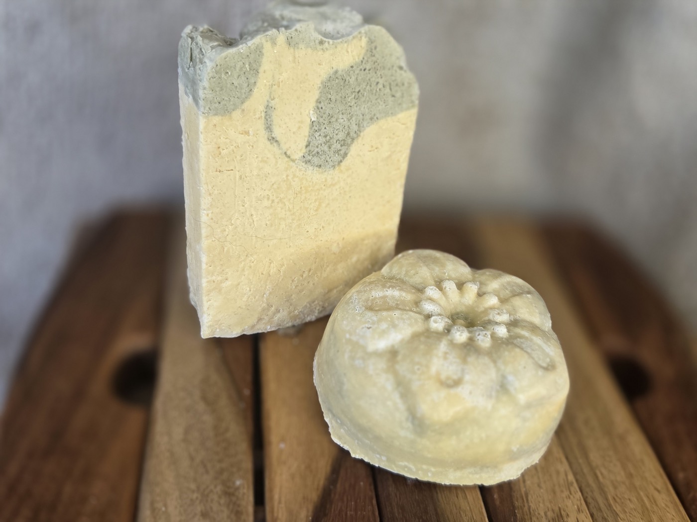 Yellow soap bar with green patches beside a green flower-molded round